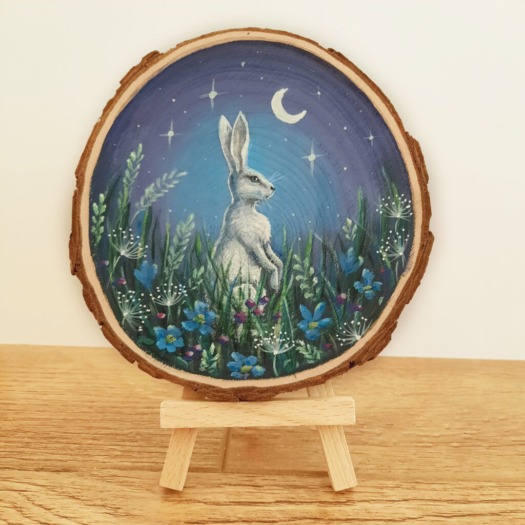 Schilderij op boomschijf haas in een magische tuin met maan