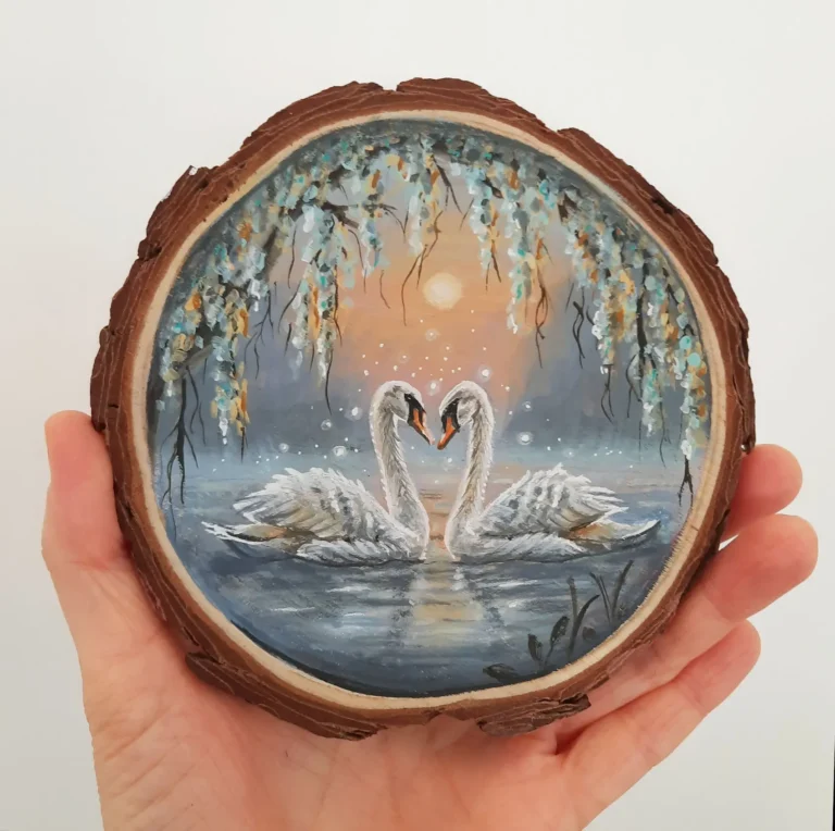 Schilderij op boomschijf van twee zwanen bij een zonsondergang