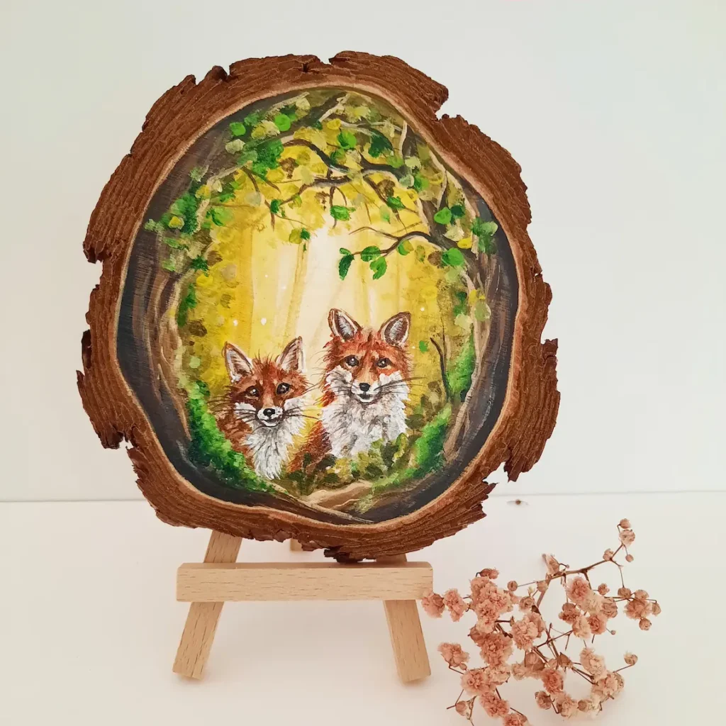 Schilderij op boomschijf van twee vosjes in een geel groen bos