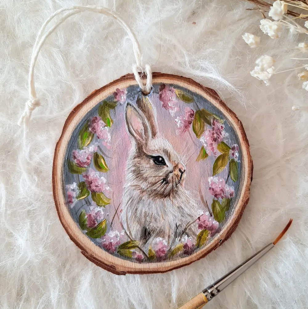 Handpainted treeslice of a white bunny surrounded by wisteria