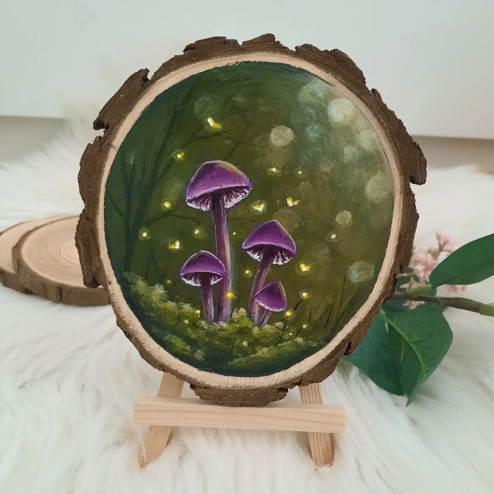 Handgeschilderde boomschijf van paarse paddenstoelen in groen bos omringd door gele vuurvliegjes